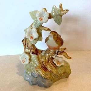 Collectible high gloss ceramic porcelain bird on perch surrounded by Holly Hocks